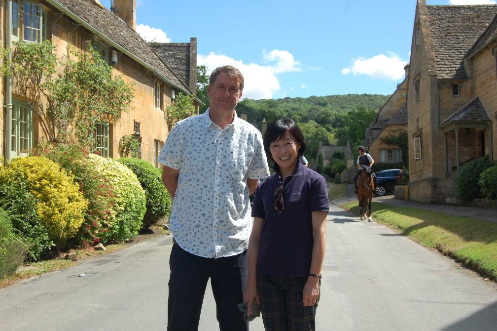 Man.tour guide standing with Japanese female.Tourist.Cotswolds.outdoors.countryside
