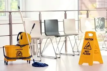 Wet floor caution sign and commercial mop bucket set up for an office cleaning task