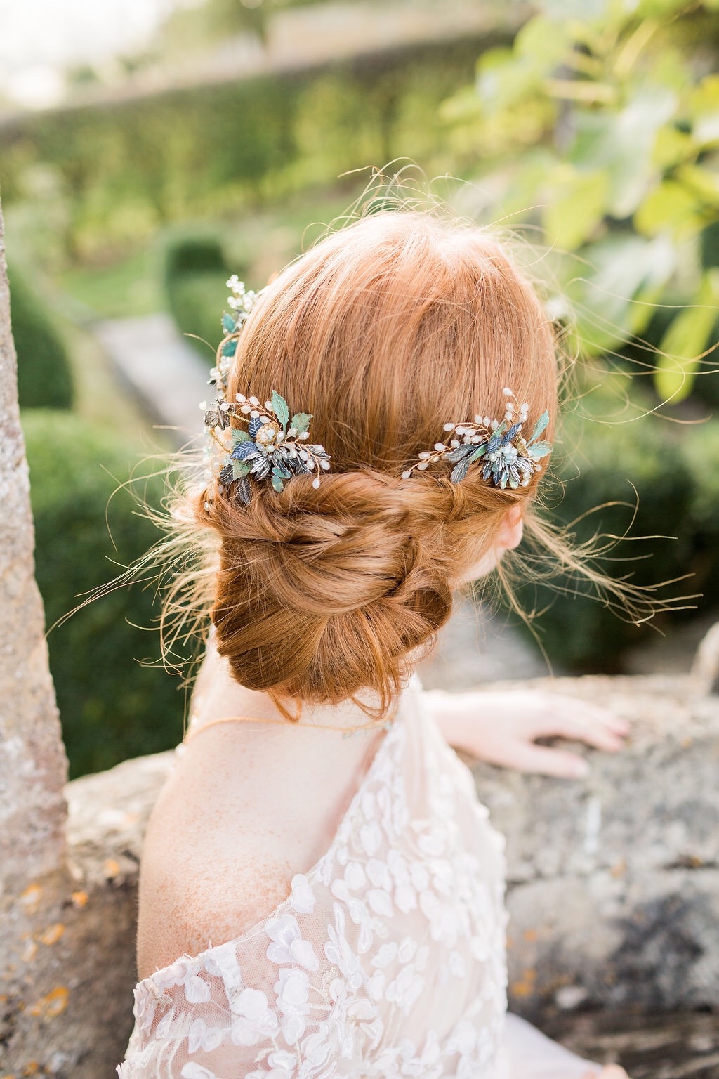A bride with auburn hair worn in a low bun wears a handmade verdigris wedding hair comb Image by Bowtie and Belle Photography