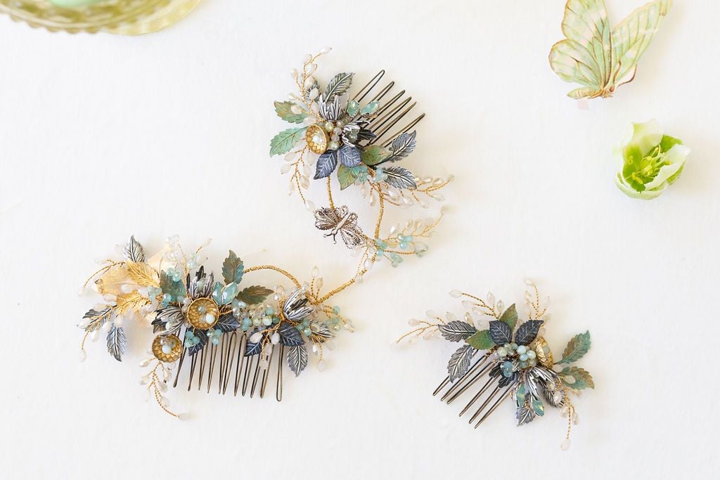 This images shows a wedding hair comb with antique silver, gold and verdigris leaves with hints of blue beadwork and a tiny antique filigree silver butterfly