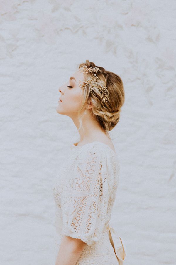 A bride wears her hair in plaited braid bun with a delicate pearl bridal headpiece worn in the side of her hair