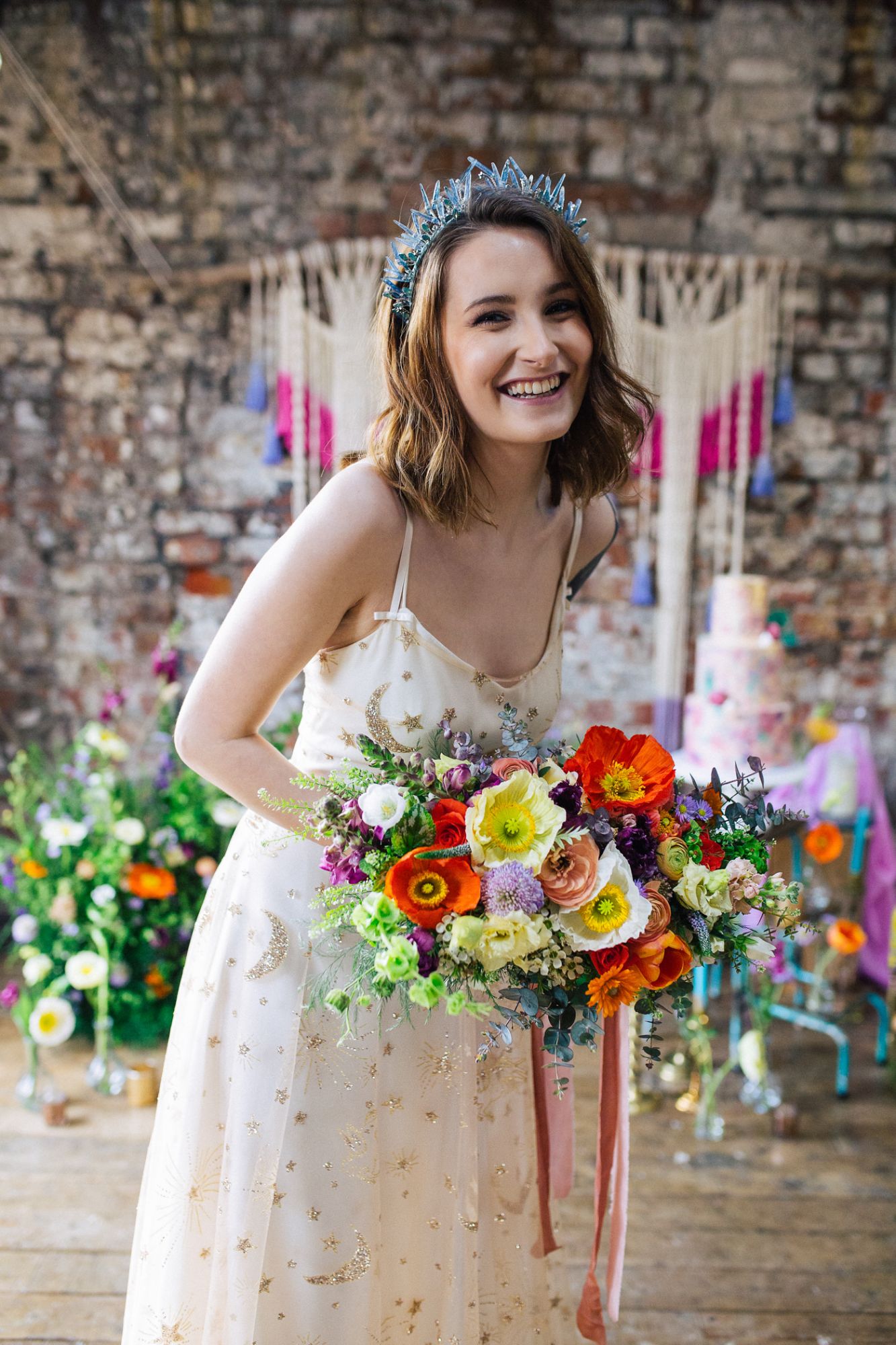 A bridal model wears a blue crystal bridal crown and carries a brightly coloured floral bouquet