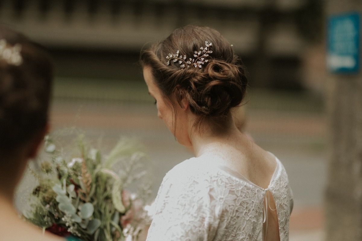 Bride wears antique lace dress with vintage style diamante wedding hair pin