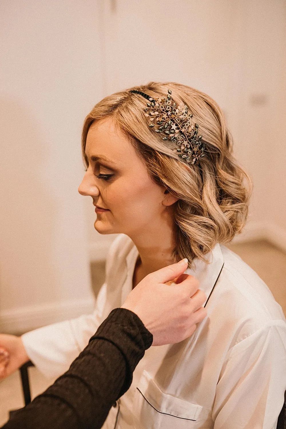 A bride getting ready ofr her wedding day and wearing a side headdress with loose waves image by Love Luella Photography