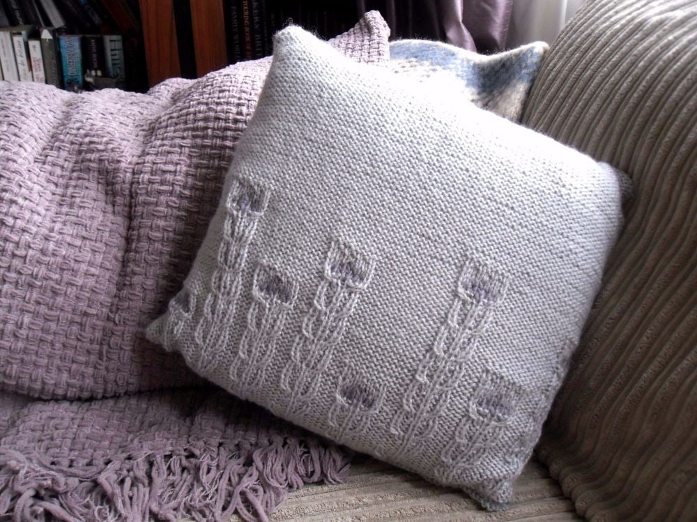 Hand knitted cushion with rows of cable flowers 
