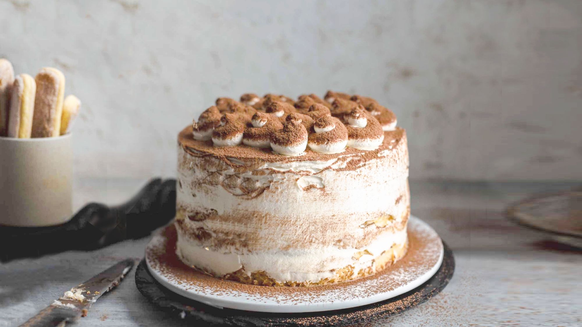Tiramisu Cake with simple piped decorations and cocoa powder