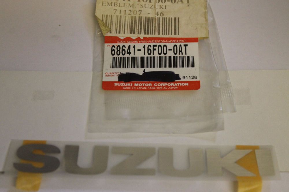 Suzuki UG110 Front Leg Shield Emblem Sticker Chrome 68641-16F00-0AT