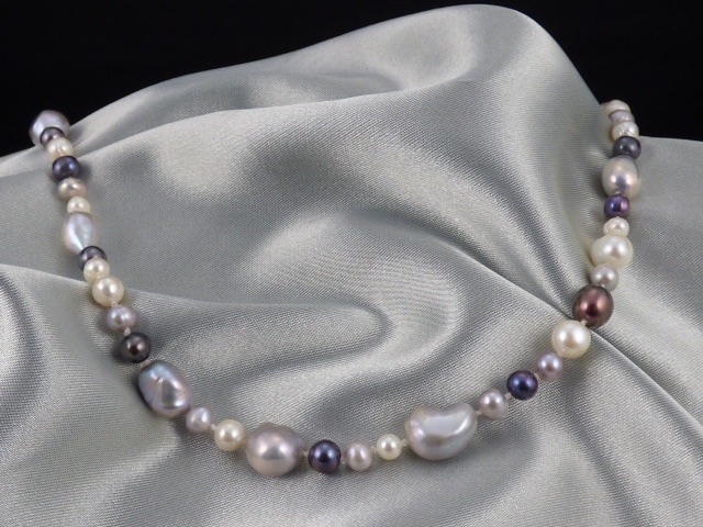 A necklace of cultured pearls of different shapes and sizes, with blue and bronze colours