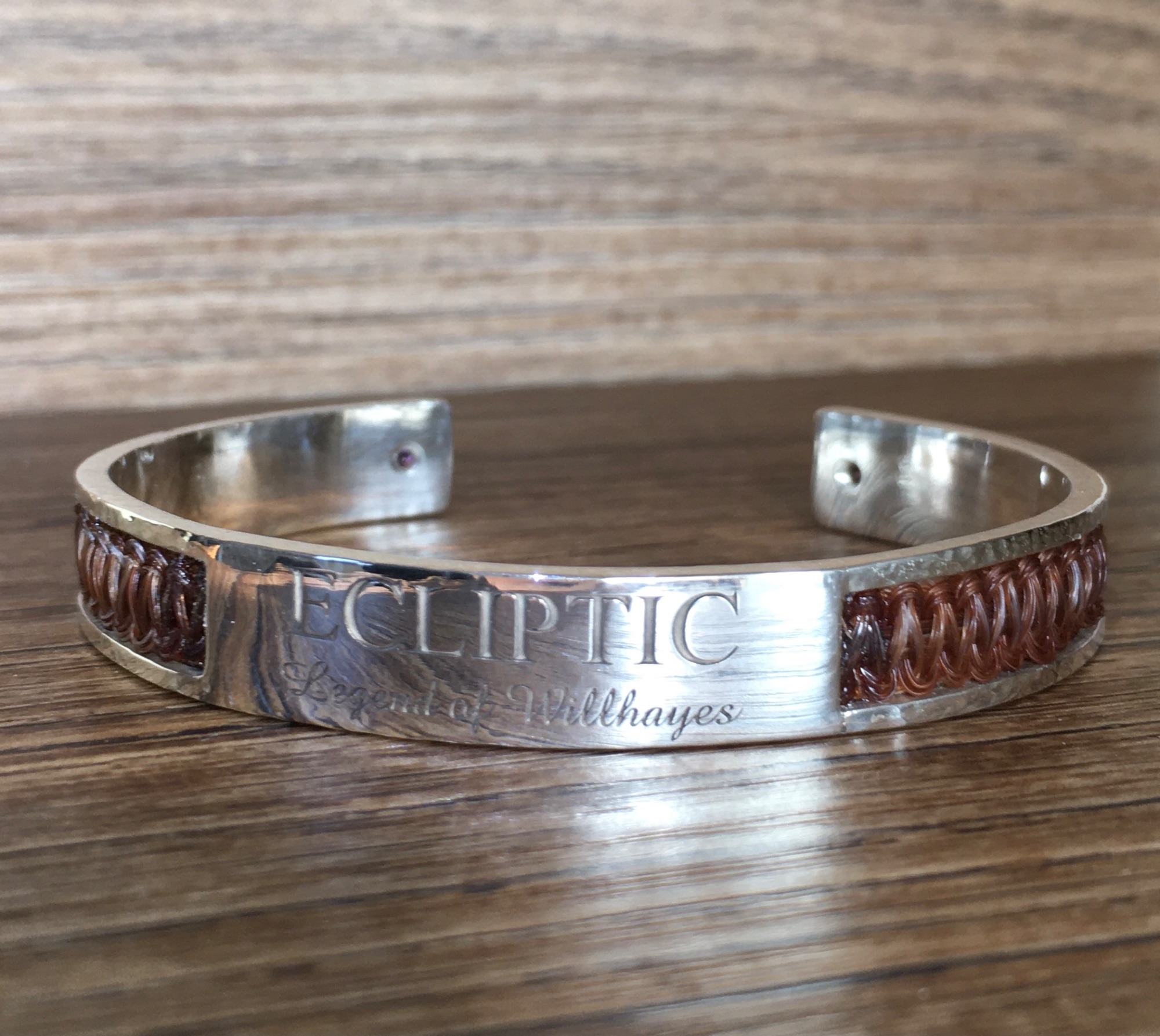 A custom made sterling silver cuff bracelet, with braided liver chestnut horse tail hair, with amethysts, and engraved text
