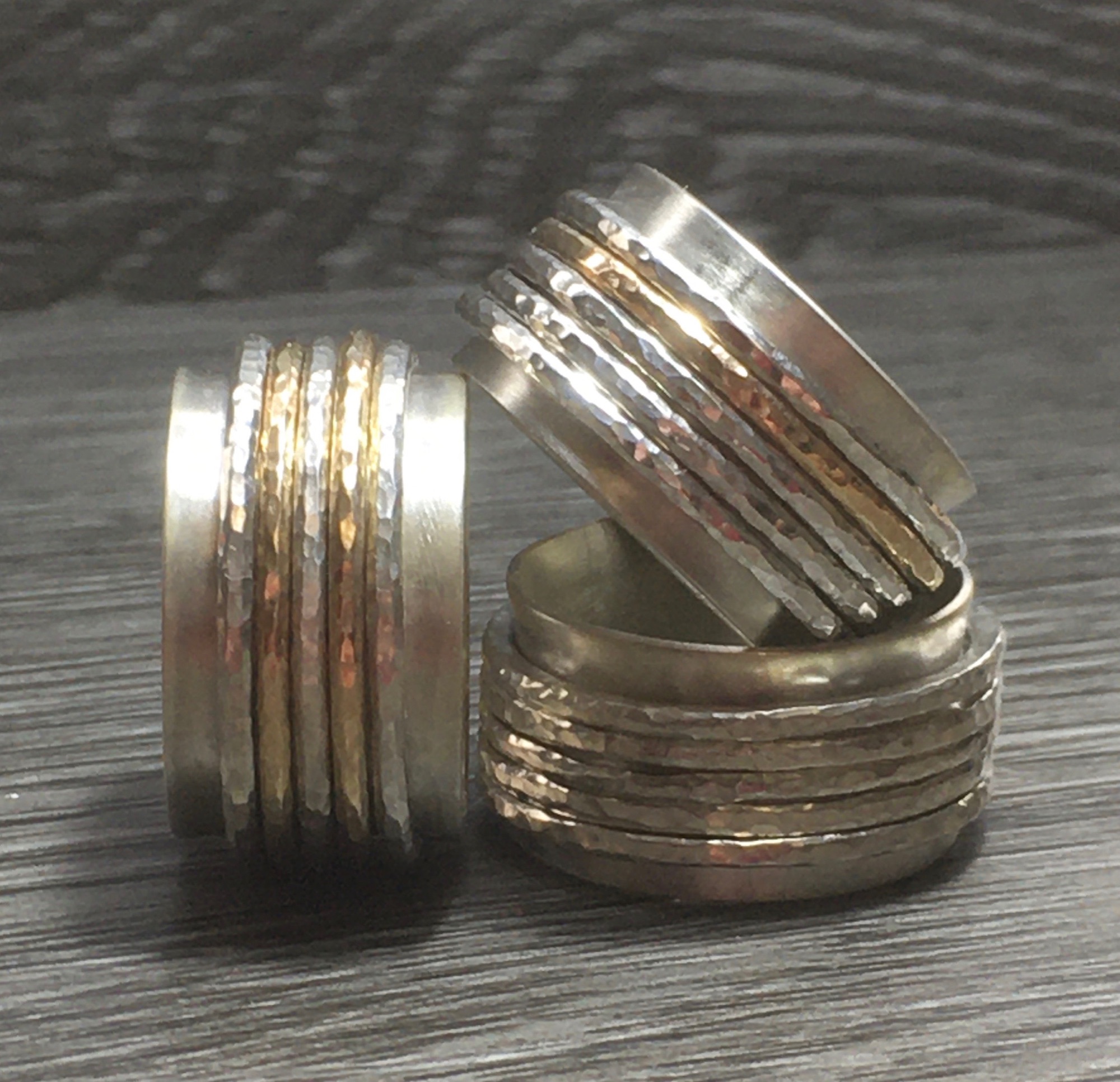 A stack of three sterling silver and yellow gold spinner rings, also known as yestling rings