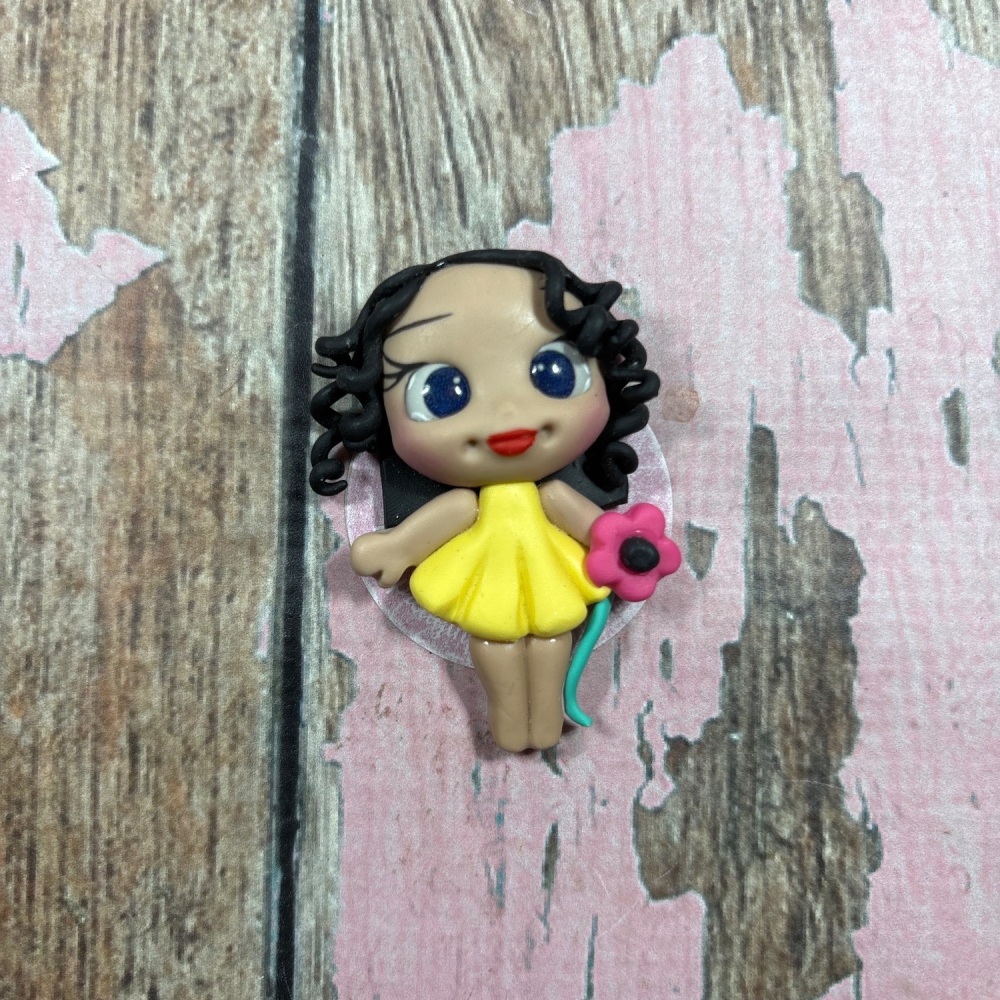 Little girl, yellow dress, pink flower, black curly hair, blue eyes