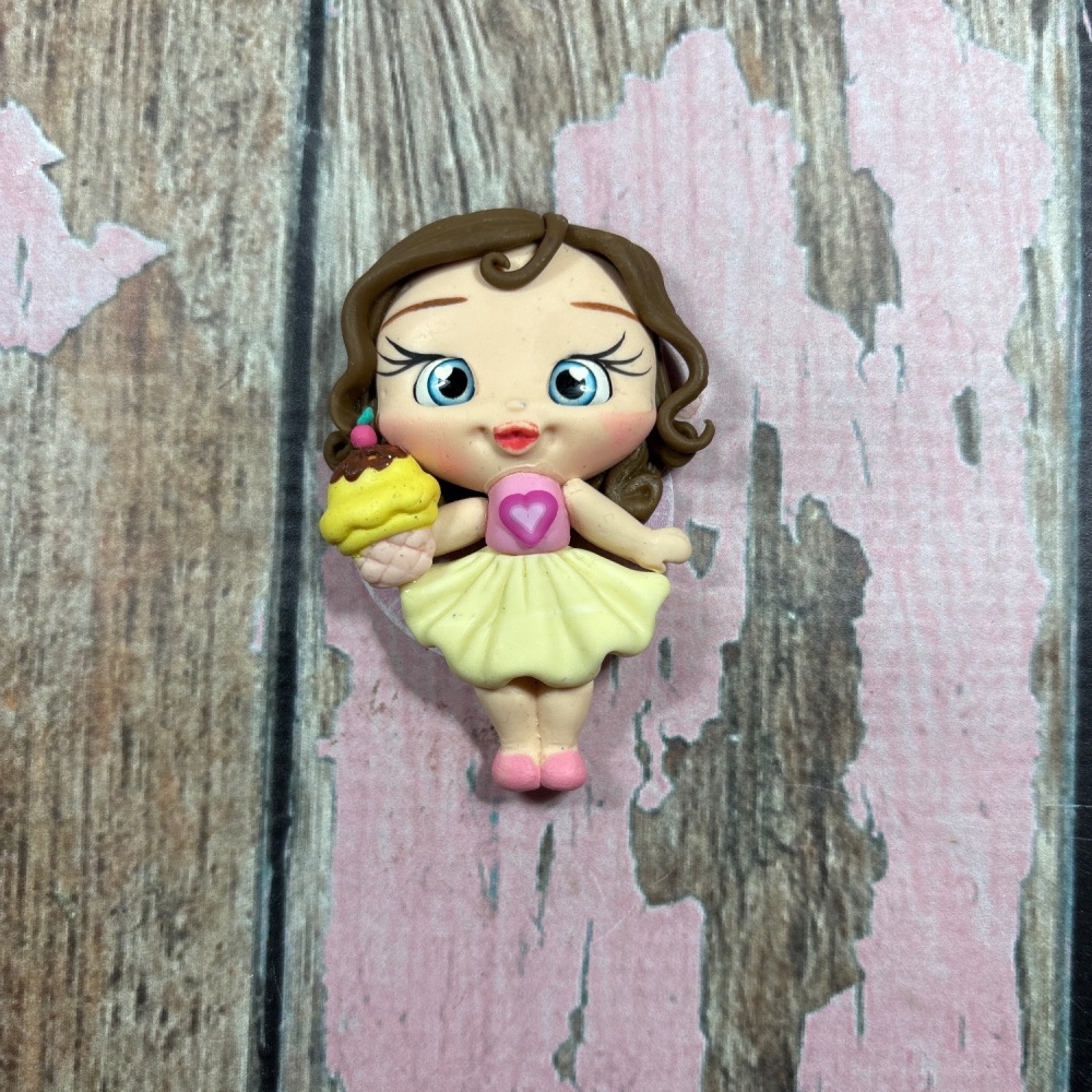 Little girl, pink top yellow skirt holding cupcake light brown hair, blue eyes