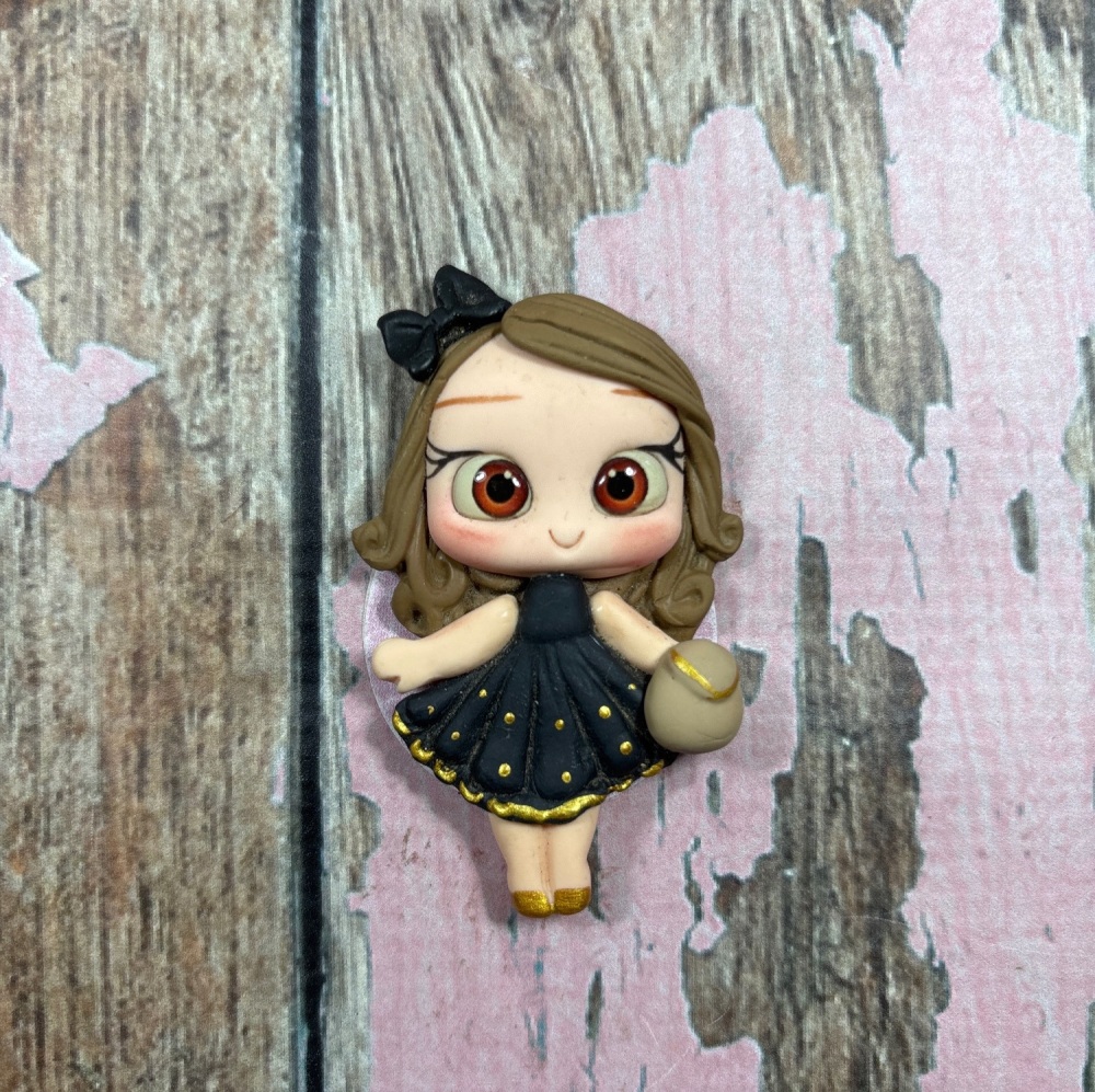 Little girl, black dress, gold polkadots with clutch bag, light brown hair, brown eyes
