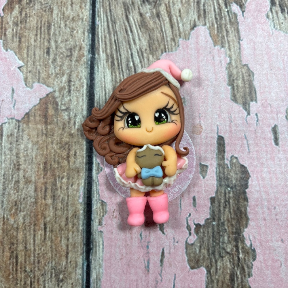 Little girl in pink dress, pink Santa's hat with gingerbread man light brown hair, green eyes