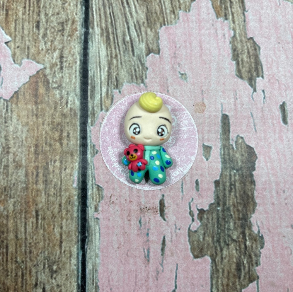 Little Cocomelon holding a teddy bear