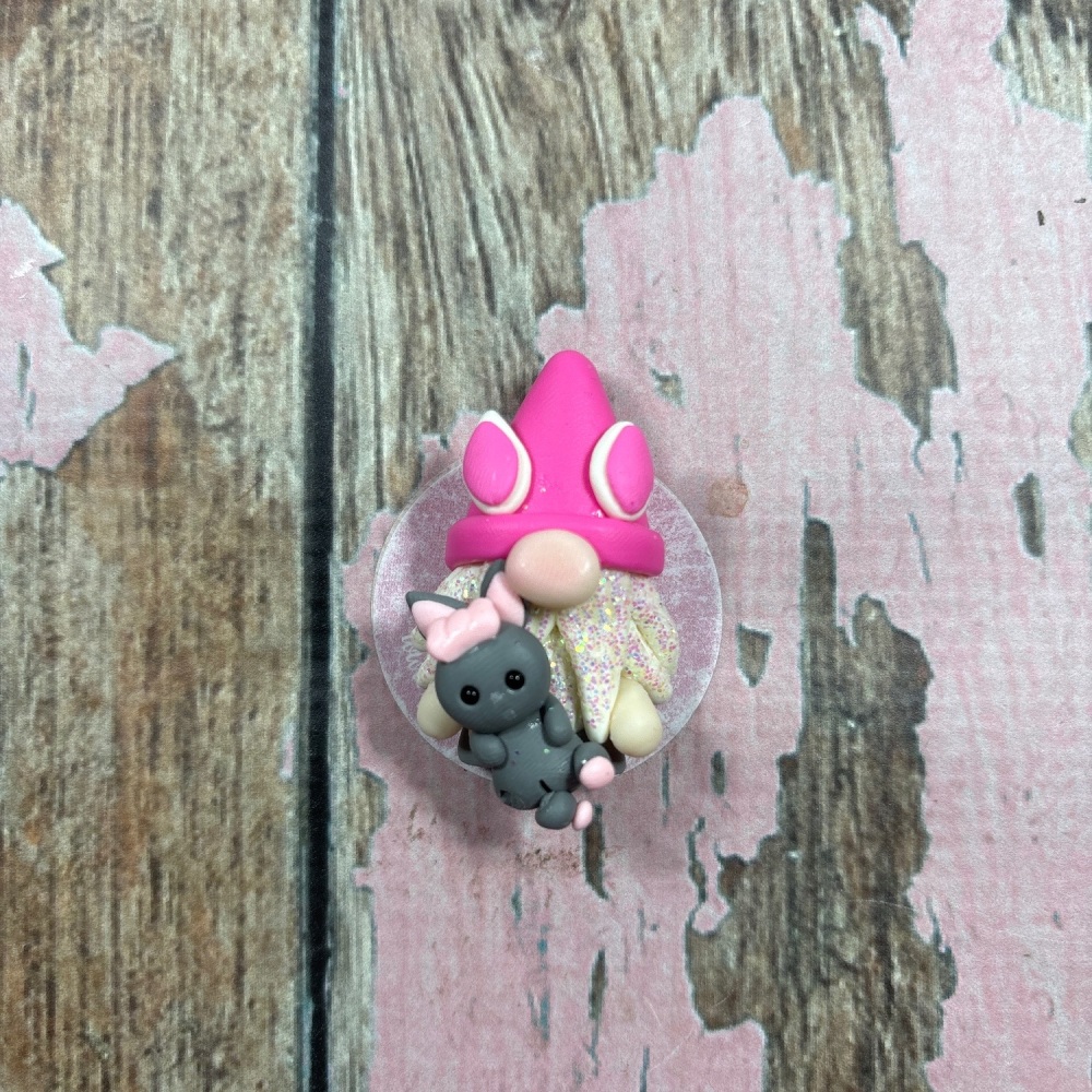 Little Gnome with a pink hat and holding a rock teddy bear with a pink bow
