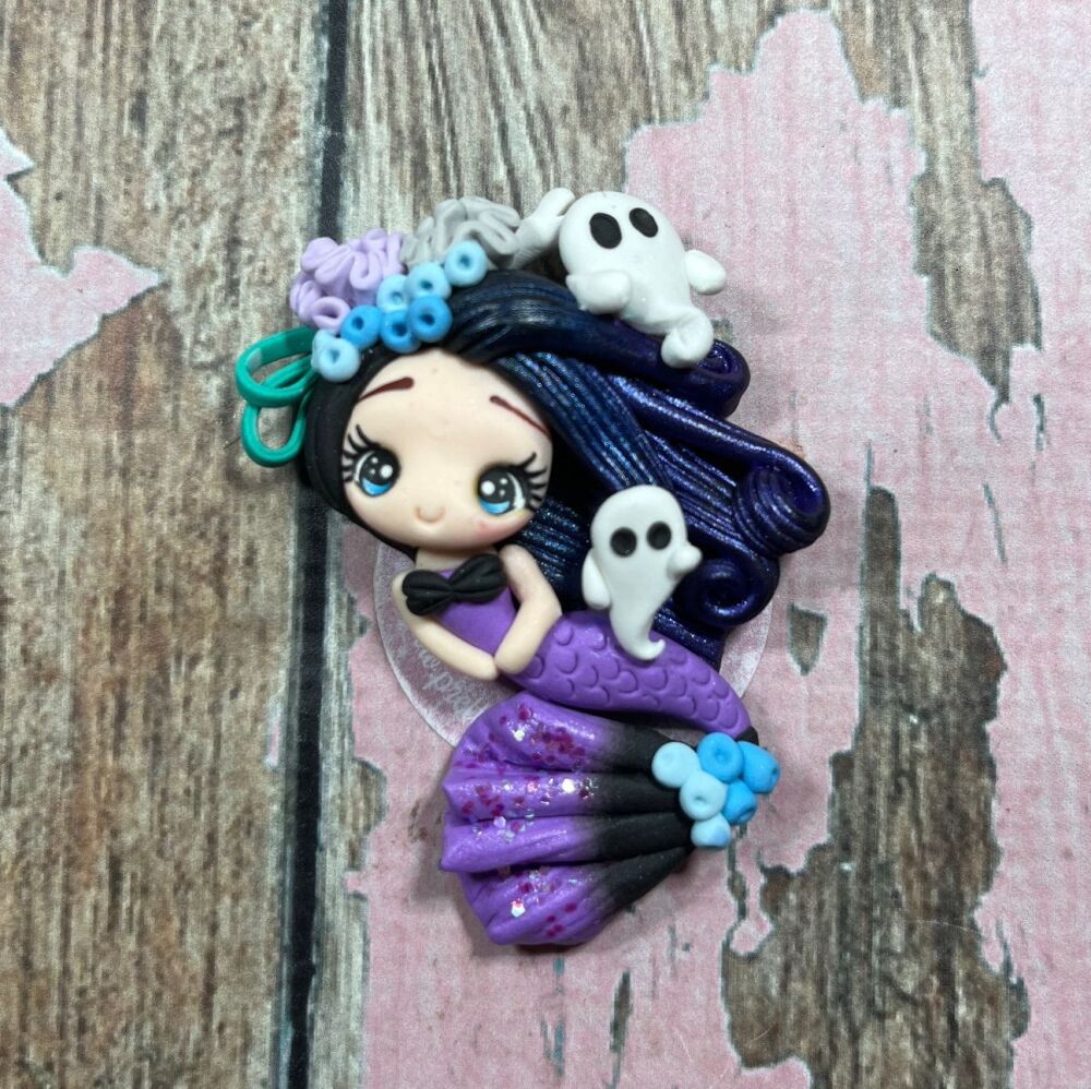 Little girl with black glittery hair and coral, a purple mermaid tail and small ghosts around her