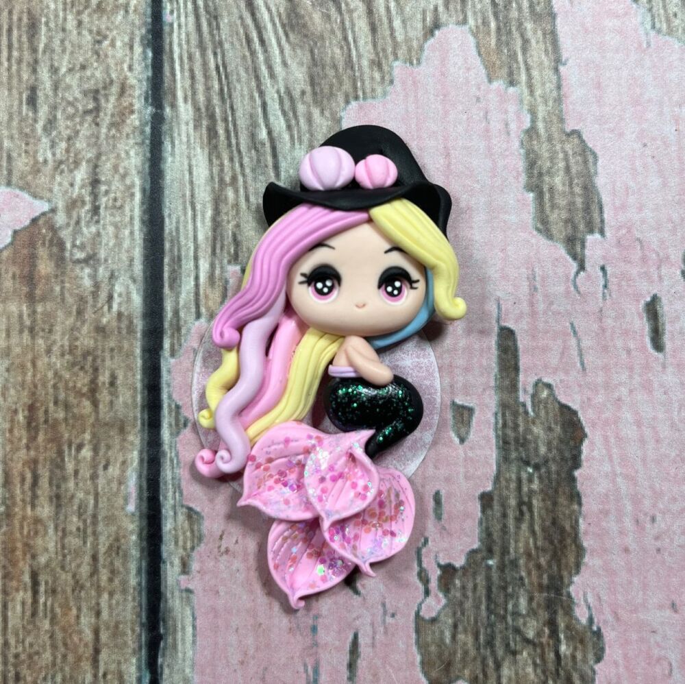 Little girl with a mix of yellow pink and blue hair, a black mermaid tail with pink fins and a witches hat