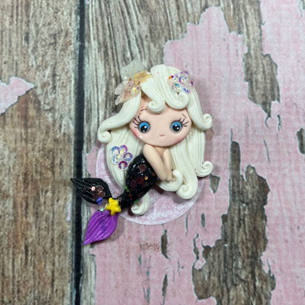 Little girl with blonde, glittery hair and a black, glittery mermaid tail