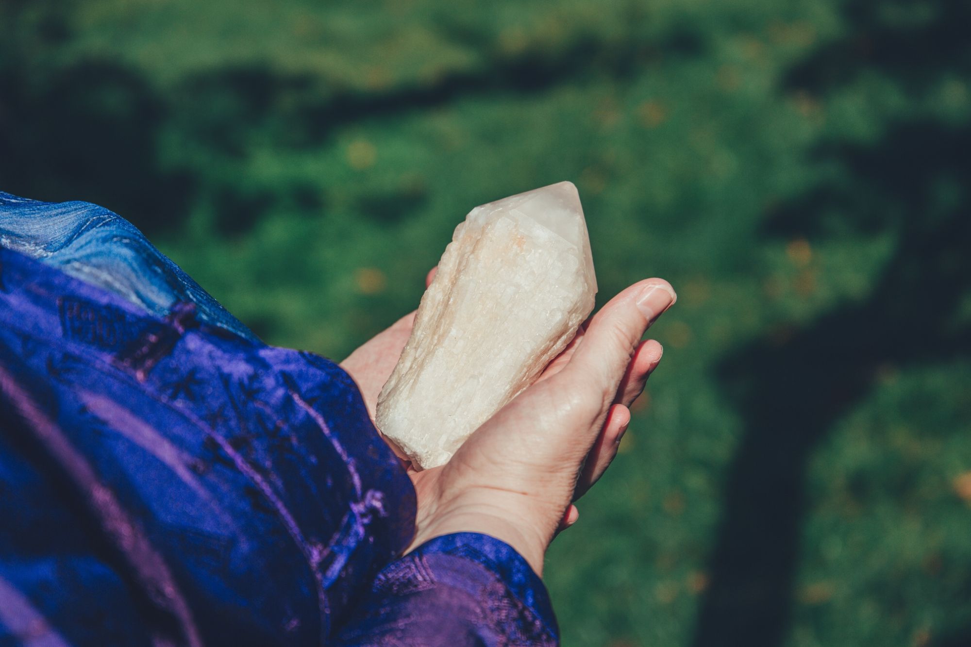 Helen's hands holding a candle quartz point