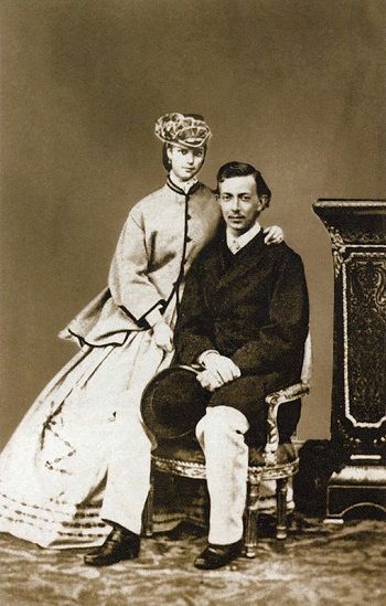 Black and white photo of Nixa of Russia sitting in a chair, with his fiancee Dagmar sitting on the arm, leaning towards him.