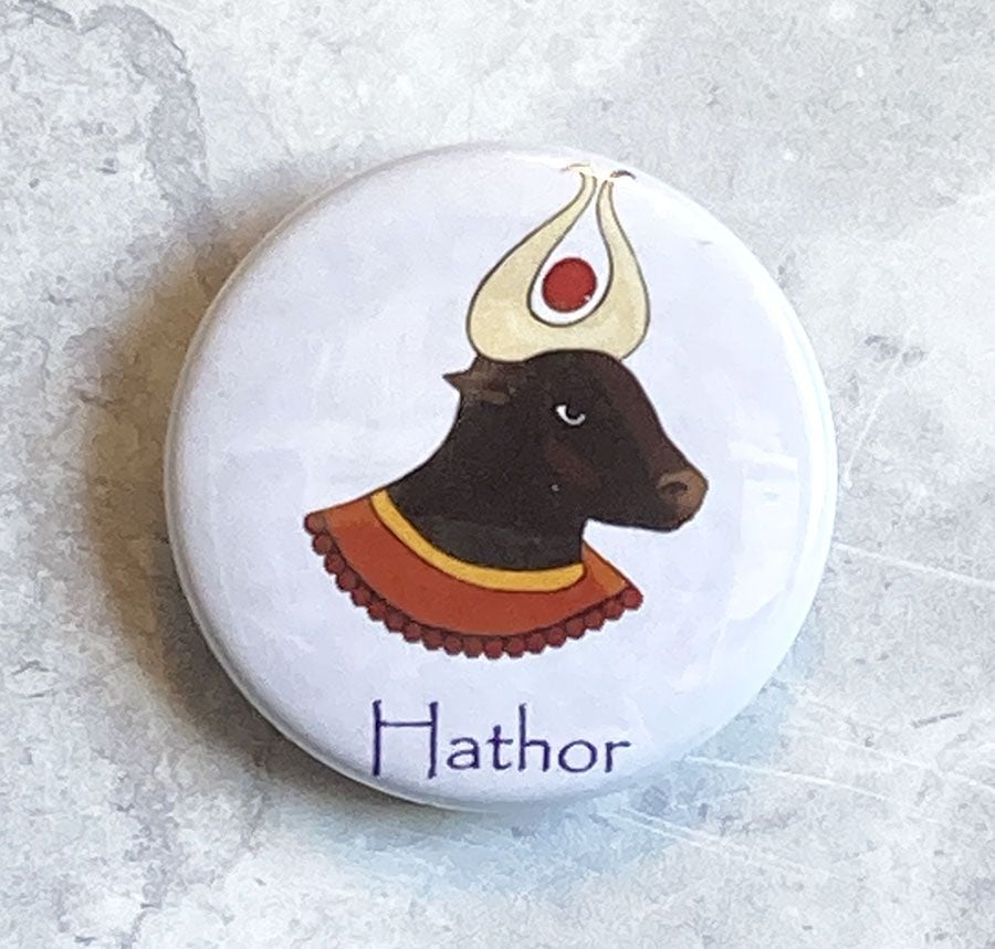 A round white badge with a digital drawing of Hathor.
