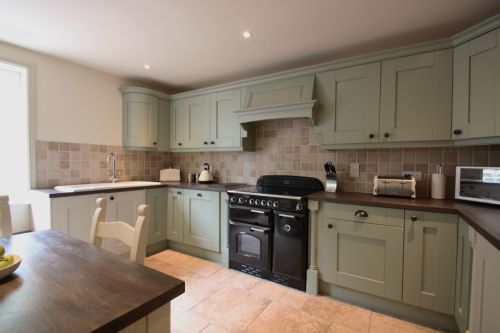 Photo of a shaker style, sage green kitchen, with a black range oven