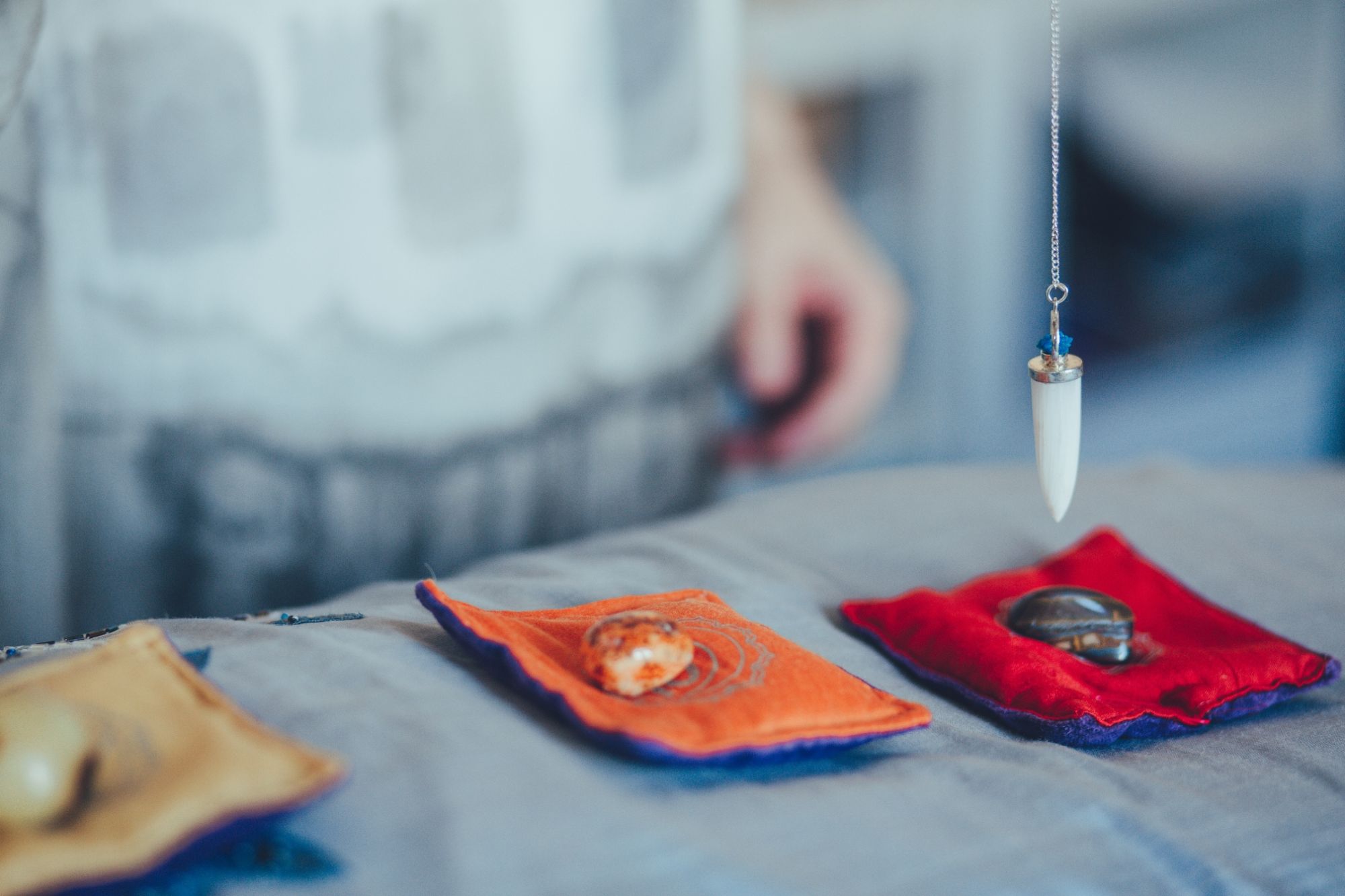 Pendulum over crystals on chakra pillows