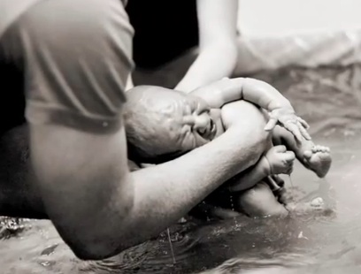 black and white photo of baby being born in water