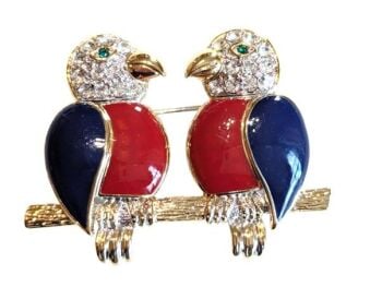 Vintage Cabouchon  brooch depicting 2 parrots in love sitting on a perch with gold plating and red and blue enamel. The eyes are green.