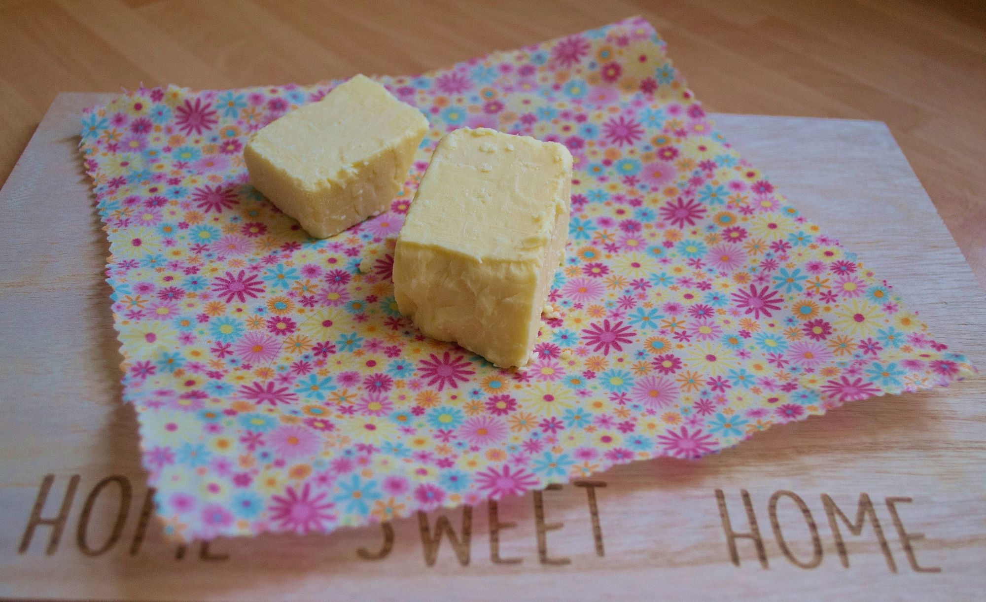 Cheese on a V-Eco Food Wrap on a wooden chopping board with the words, Home Sweet Home