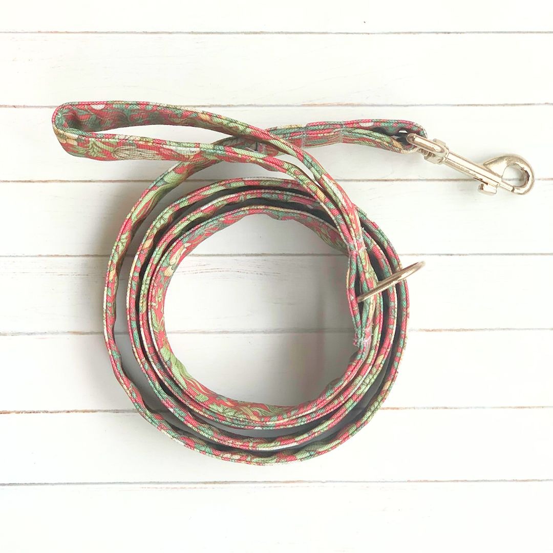 William Morris Strawberry Thief crimson dog lead coiled on a white wooden floor. Stylish dog accessories UK. Luxury dog walking accessories.