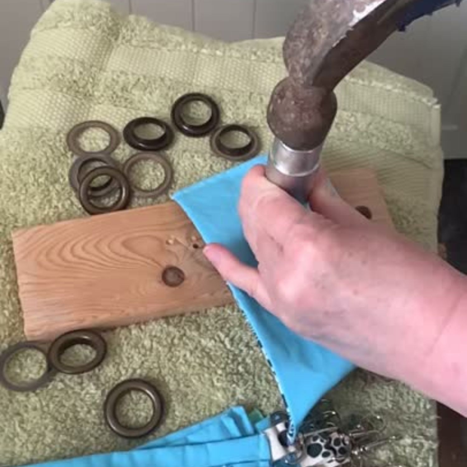 The hands of a woman hammering grommets into poo bag pouches