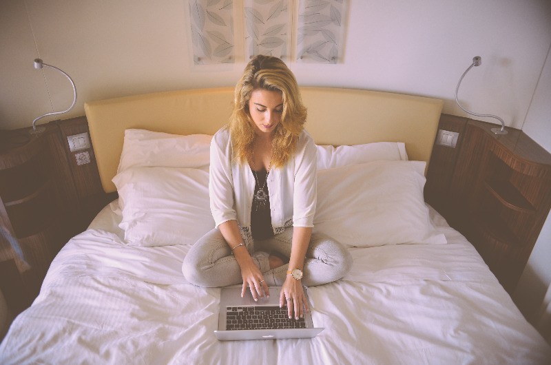woman working on laptop from hotel bed