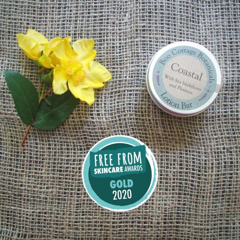 Coastal lotion bar in tin with yellow flower and gold award on hessian background