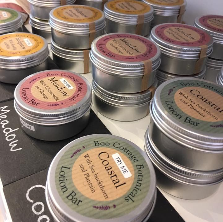 Stacks of round aluminium tins with colourful lotion bar labels