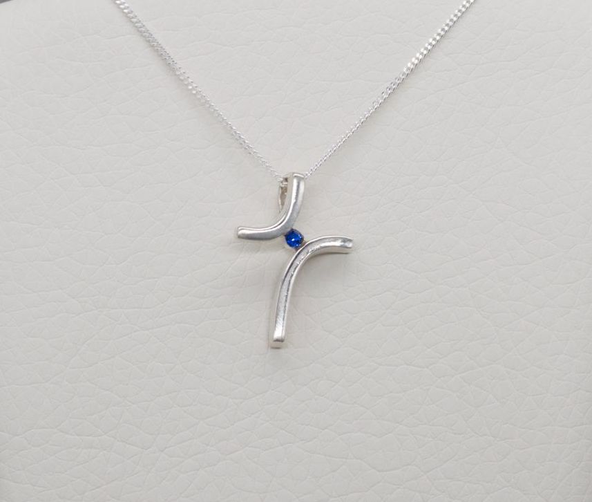 Small sterling silver abstract cross necklace with a blue stone