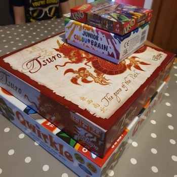 Stack of board games, including Qwirkle, Tsuro, Uno and Colour Brain