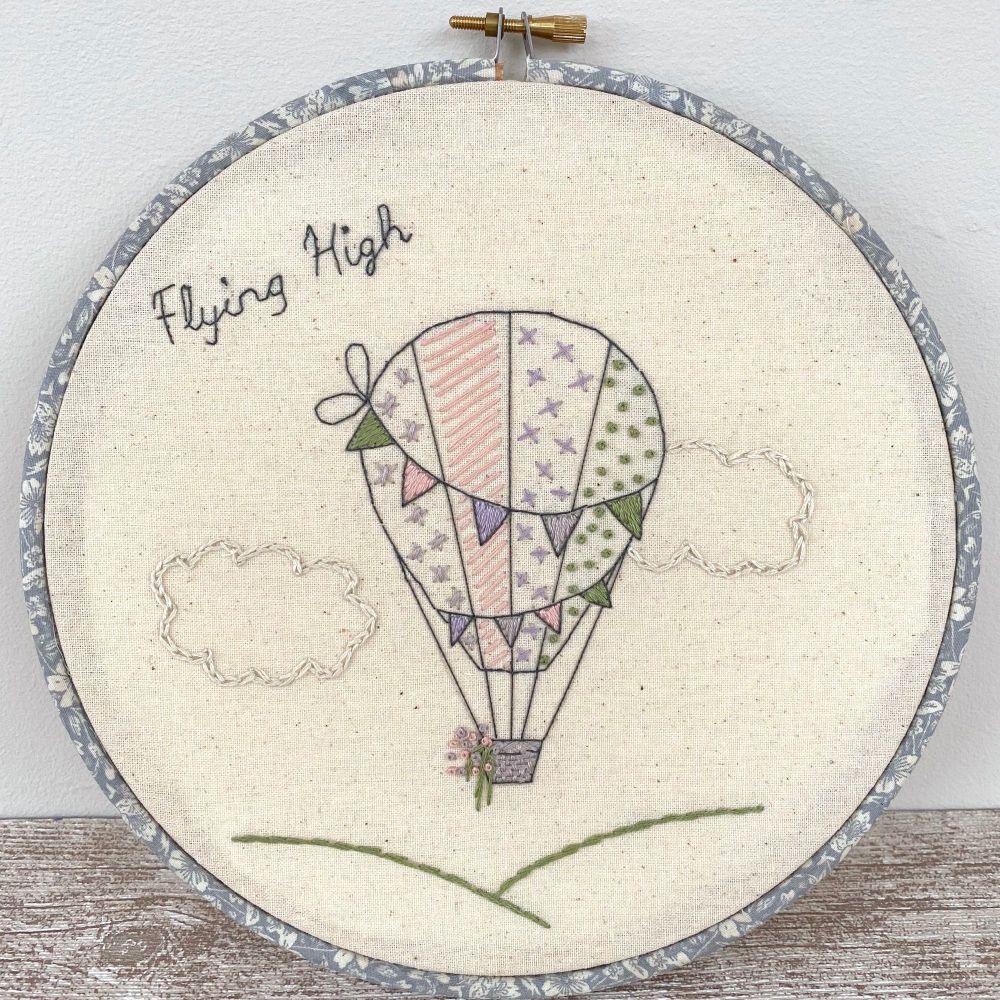 An colourful embroidered hot air balloon embroidery sampler standing against a wall. Made by Just Sew Helen