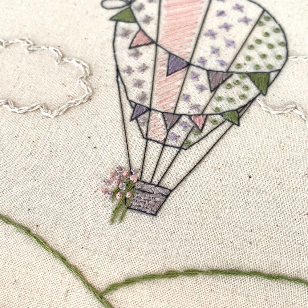 Basket and stem stitch on an embroidered hot air balloon using pink, green and purple theads