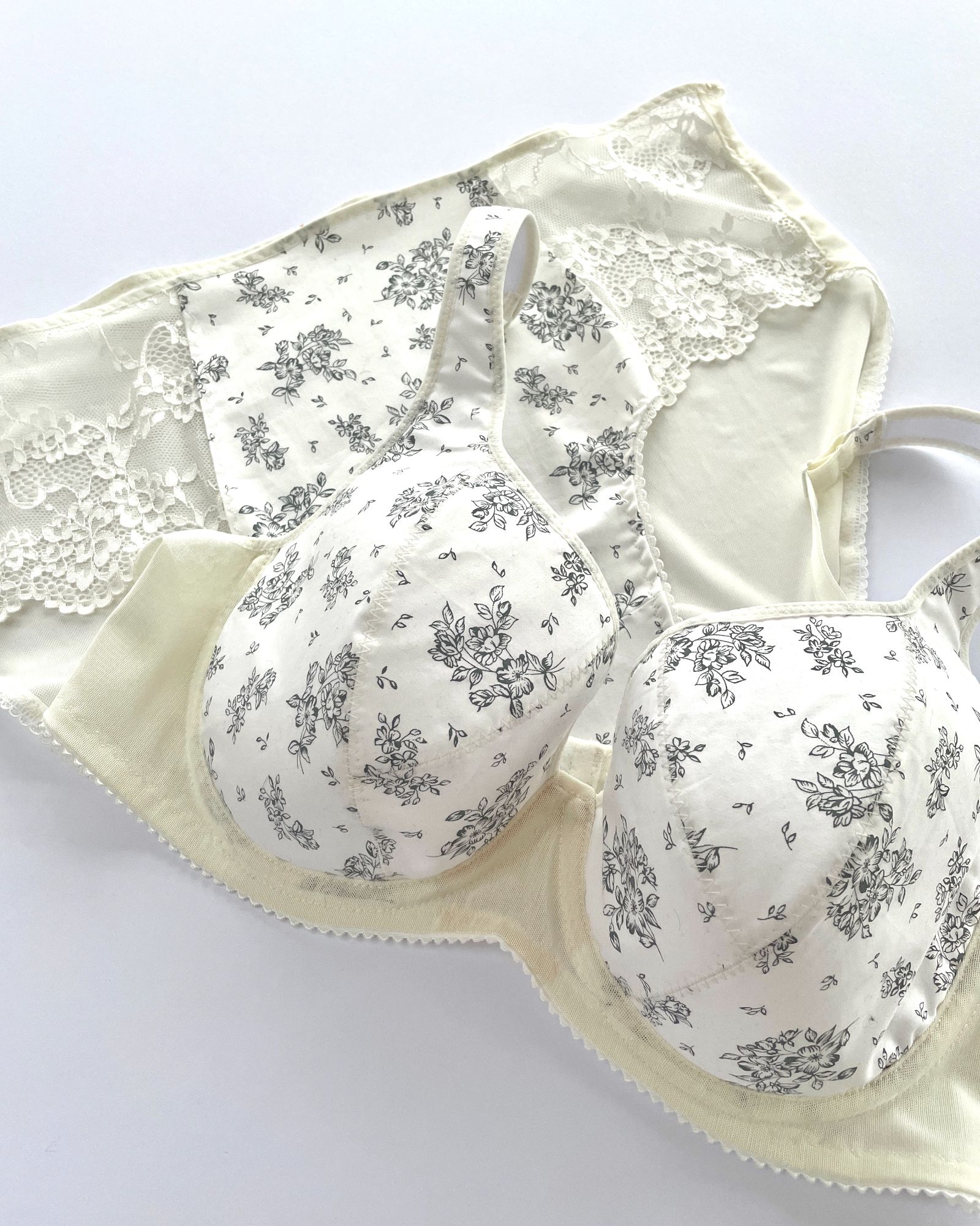 Ivory and grey flowers underwired bra and lace birefs set laid on a white background.