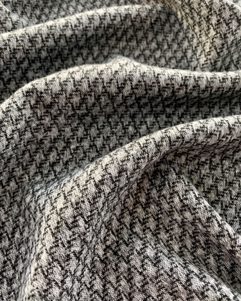Soft shades of grey textured wool looking fabric lying ruffled on a surface.