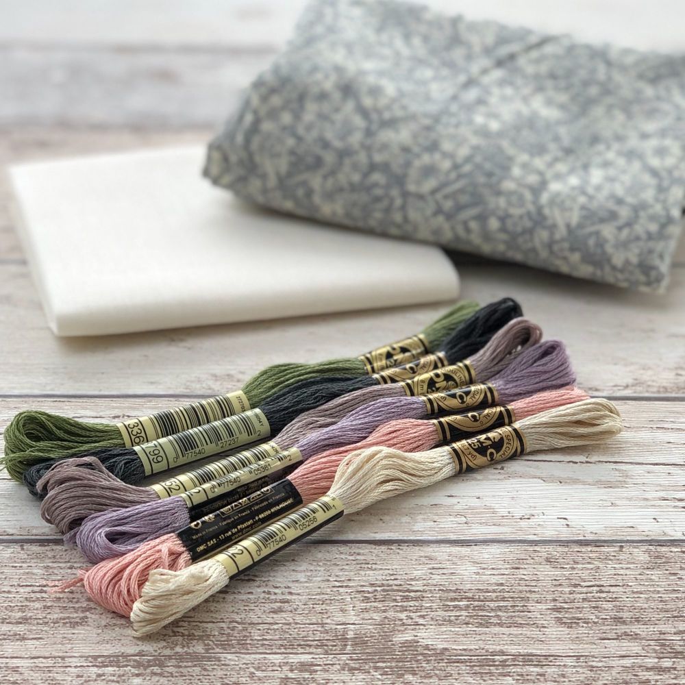 Six embroidery Threads and two fabrics, a grey floral and natural cotton placed on a wooden background