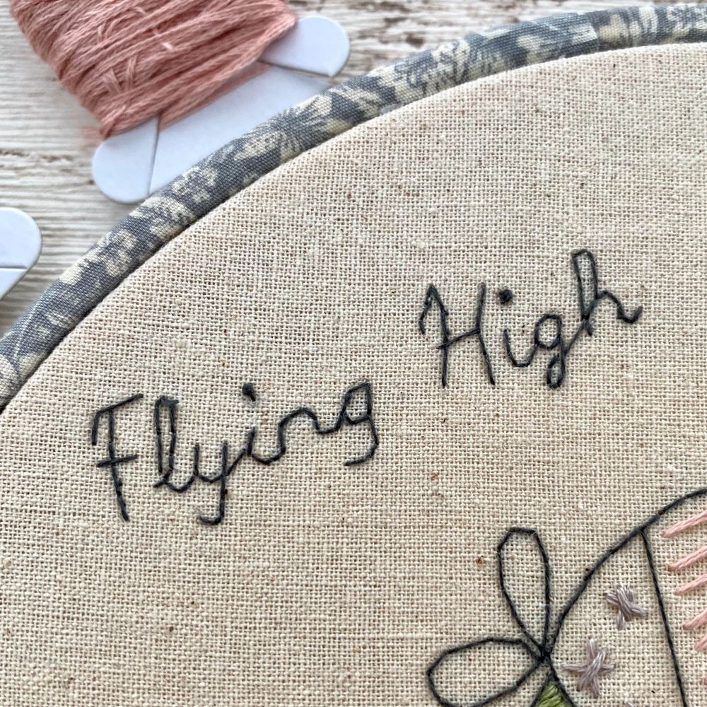 Black flying high stitched lettering on a linen background fabric