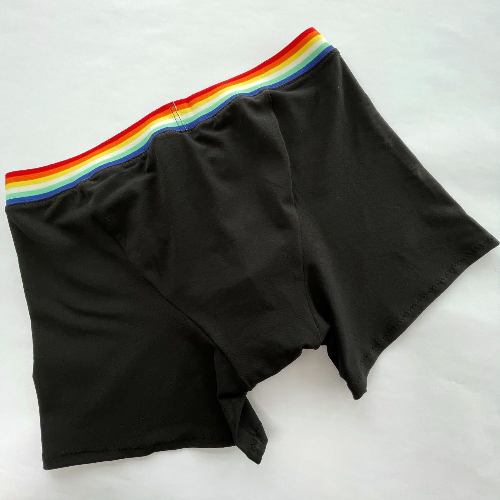 Back view of a pair of Mens Boxer Briefs made with black jersey fabric and rainbow striped waist elastic.  