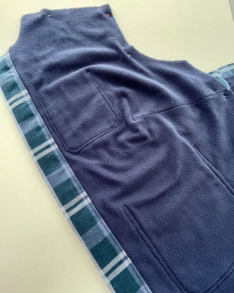Inside of a navy jacket showing the fleece lining and stitching around the pockets