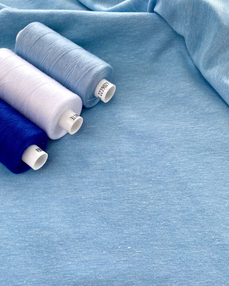 A photograph of Cotton Jersey Melange Fabric with 3 reels of cotton