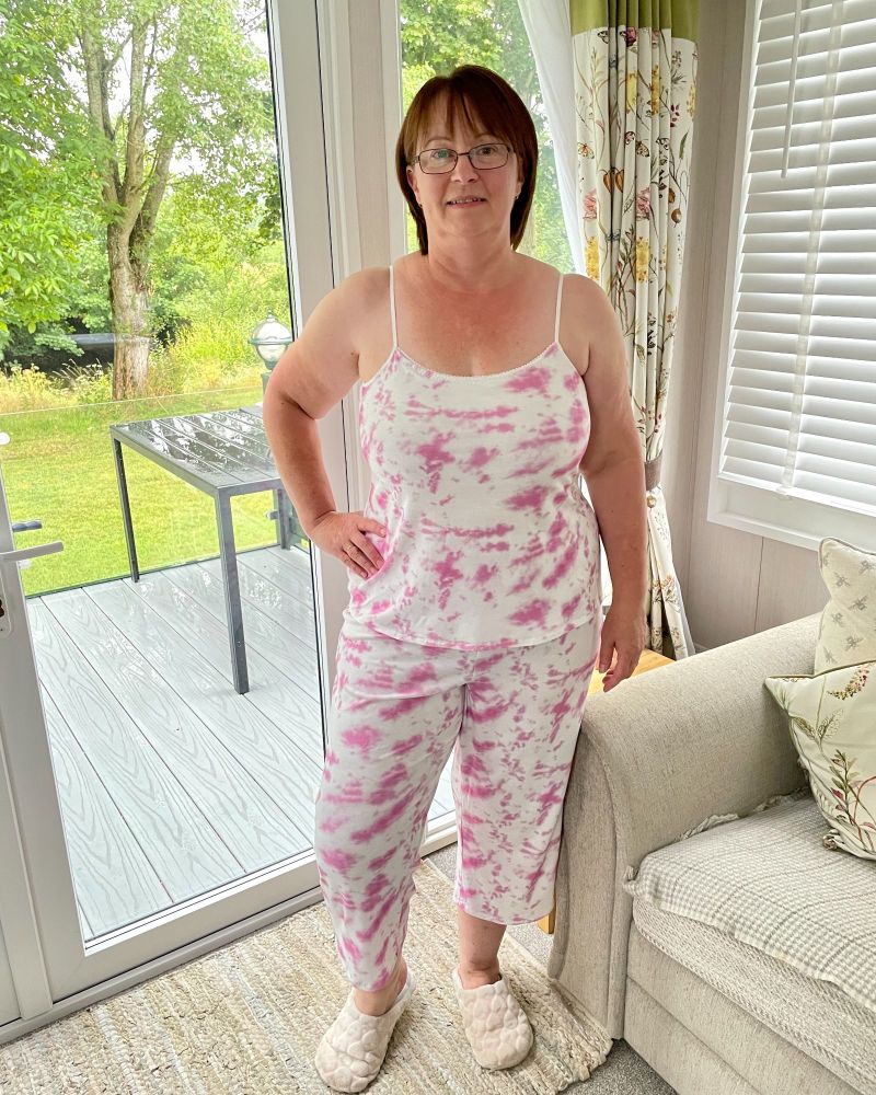 A lady wearing a pink & white tie dye cropped trousers and cami set, standing in front of a patio