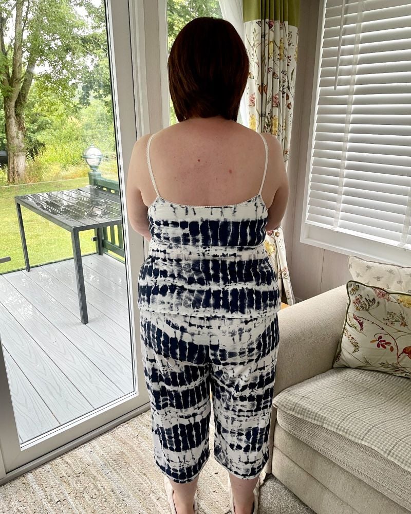 The back of lady wearing a navy & white tie dye cropped trousers and cami set, standing in front of a patio