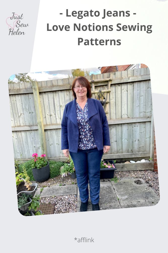 A lady standing in a garden in front of a fence wearing a navy jacket and blue jeans